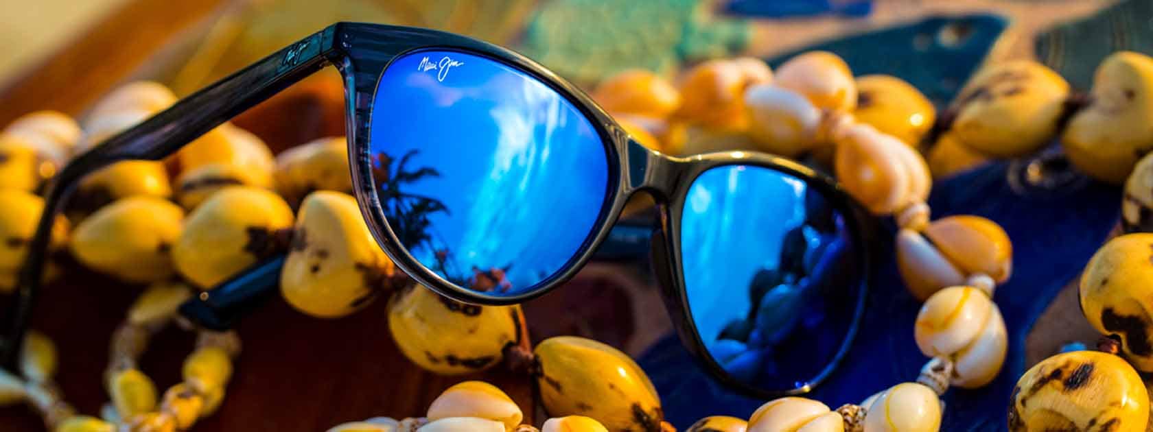 occhiali da sole con lenti blu mostrati sopra a collane di conchiglie
