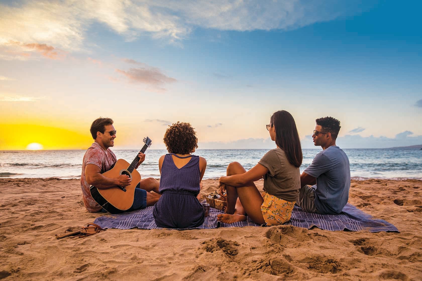 Quattro persone in una spiaggia con una chitarra