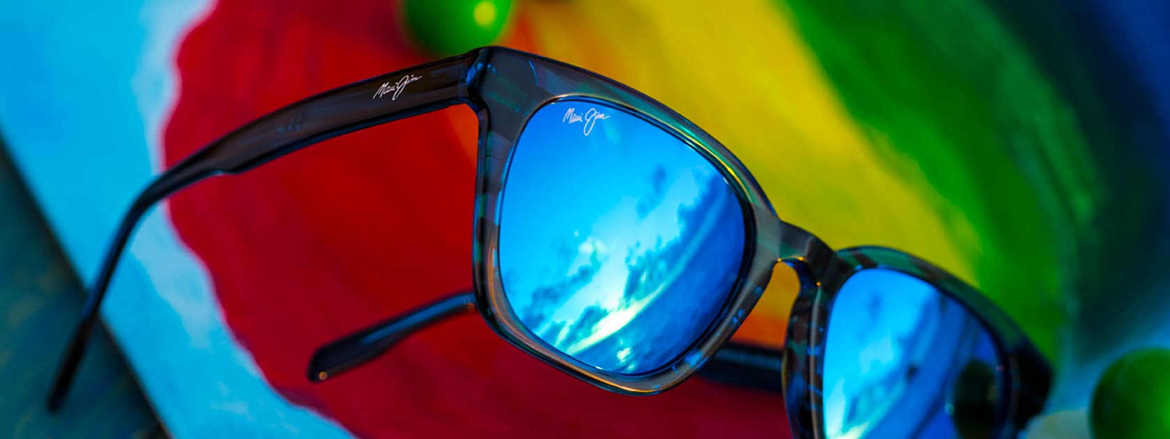 occhiali da sole con montatura blu e lenti blu davanti ad uno sfondo colorato